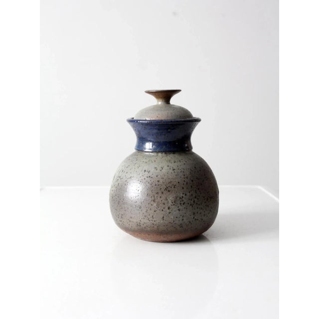 his is a signed studio pottery jar dated 1978. The hand-crafted ceramic vessel features a speckled gray glaze with blue...