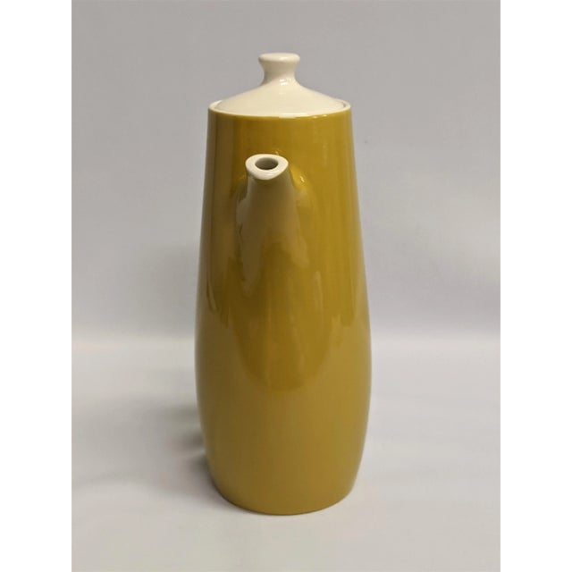 A stylish mustard and white coffee or tea server. The ceramic pot has a artistic minimalist style with the wide handle and...