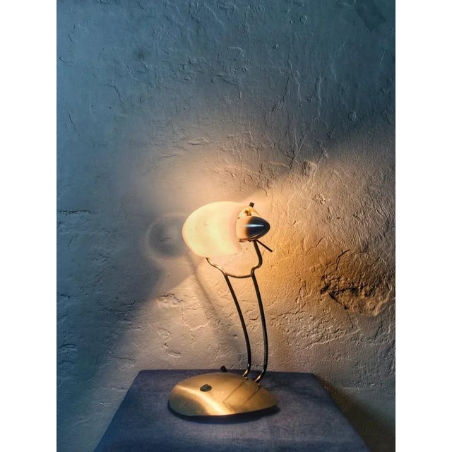 Table lamp on a stainless steel base, with an adjustable shade made of matte white glass. It evokes the style of Marlene,...