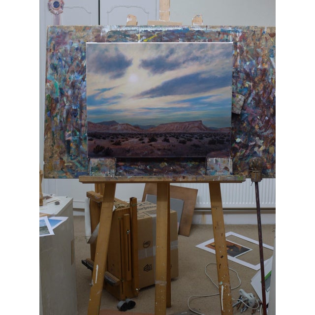 This oil painting captures a vast desert landscape under a softly illuminated sky, where muted hues of pink, blue, and...
