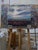 This oil painting captures a vast desert landscape under a softly illuminated sky, where muted hues of pink, blue, and...