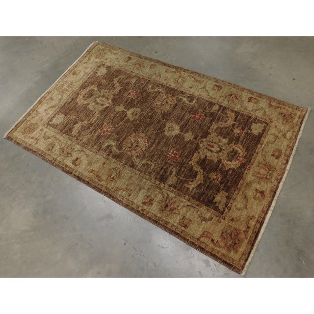 Floral display on light brown field within tan border. Hand spun vegetable dyed wool pile on cotton foundation.