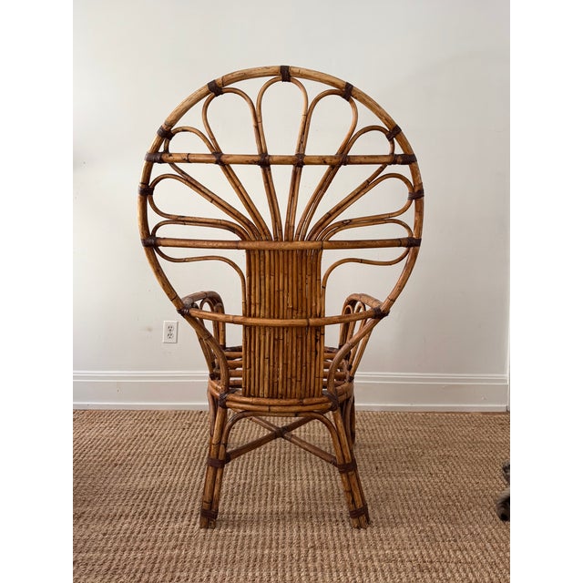 This vintage bent rattan peacock armchair features a sculptural fan-shaped back with beautifully curved cane detailing and...