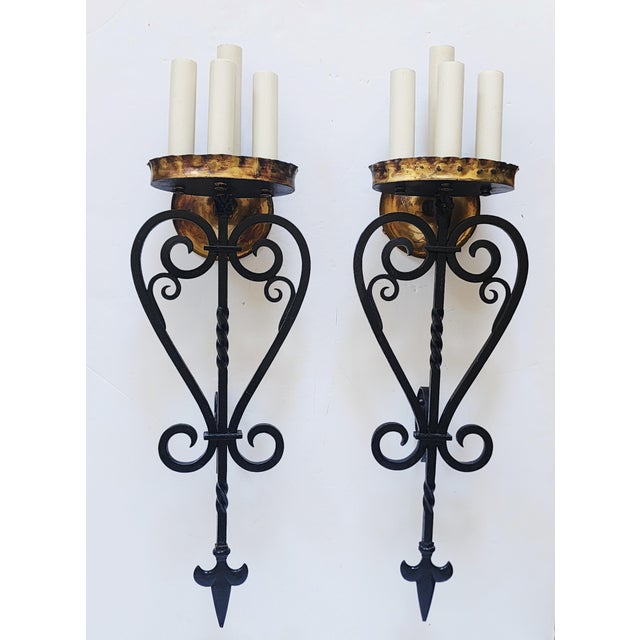 Impressive pair of painted wrought iron and gilded metal Spanish Revival style wall sconces. The sconces have elegant...