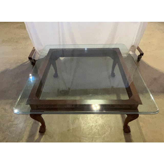 An elegant vintage Chippendale-style mahogany coffee table featuring a distinctive square silhouette. The table boasts an...