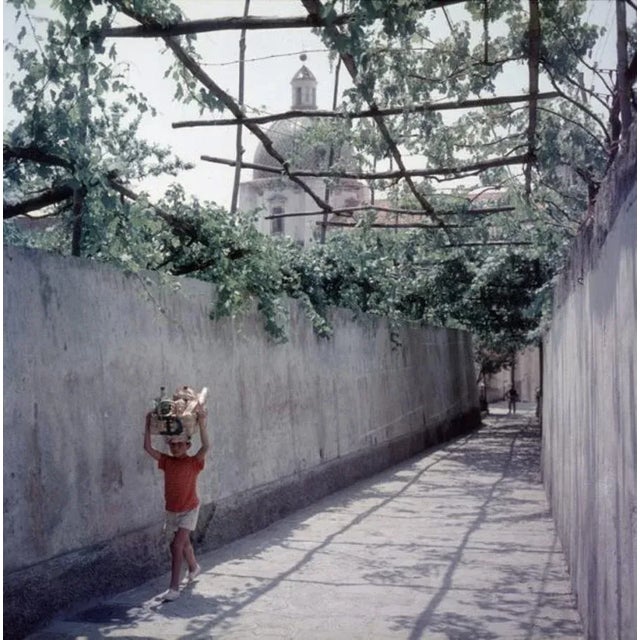 Positano 1958 by Slim Aarons Slim Aarons Limited Estate Edition A little boy carries a basket of groceries home in...
