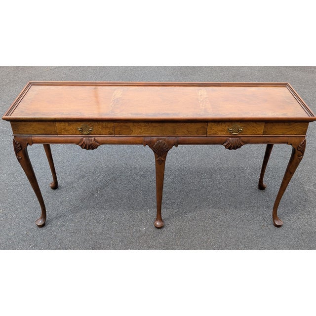 This exceptional console table attributed to Baker Furniture beautifully showcases the timeless elegance of classic Queen...
