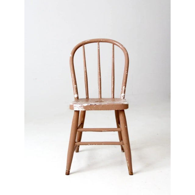 This charming vintage bow-back Windsor chair features a beautifully weathered farmhouse finish in a soft pinkish-beige,...