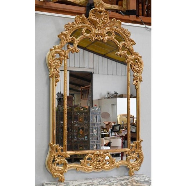 Large golden mirror with Pareclyrosis, in the Regency style, resting on 2 feet with scrolls and acanthe leaves, which go...