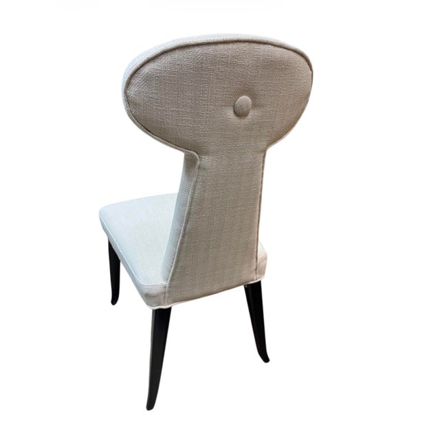 Accent chair or dining chair features a sculptural, high back with a distinctive rounded “keyhole” or paddle-shaped...