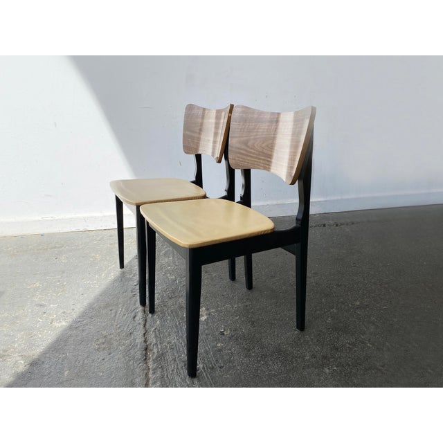 A set of two mid-century, vintage dining chairs featuring curved backrests with a wood grain laminate paired with...