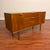 Vintage small mid-century teak sideboard with sculpted teak door and drawer pulls, gently curved front, and tall tapered...