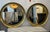 A large pair of decorative round mirrors with concave brass frames. The mirrors have four antiqued square patches applied...