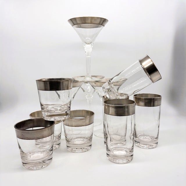 An iconic mid-century barware set by Dorothy Thorpe, featuring her signature silver band overlay on clear glass. This...