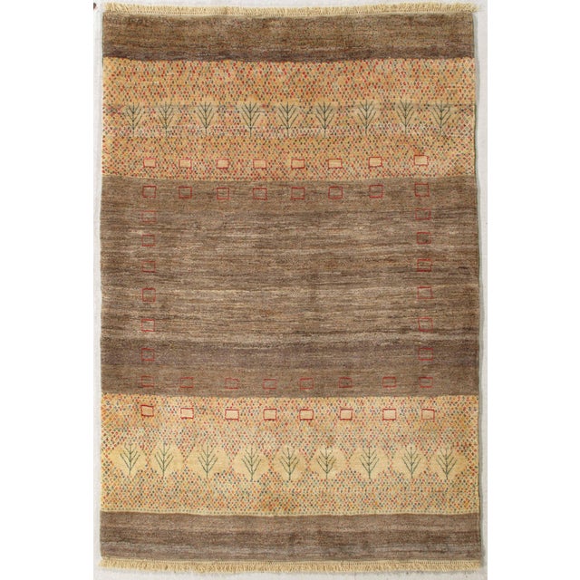Vintage hand-knotted Persian Gabbeh rug featuring a soft, earthy field framed by patterned bands with stylized tree motifs...