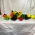 This image shows a large, vibrant collection of vintage Murano-style hand-blown glass fruits and vegetables, arranged...