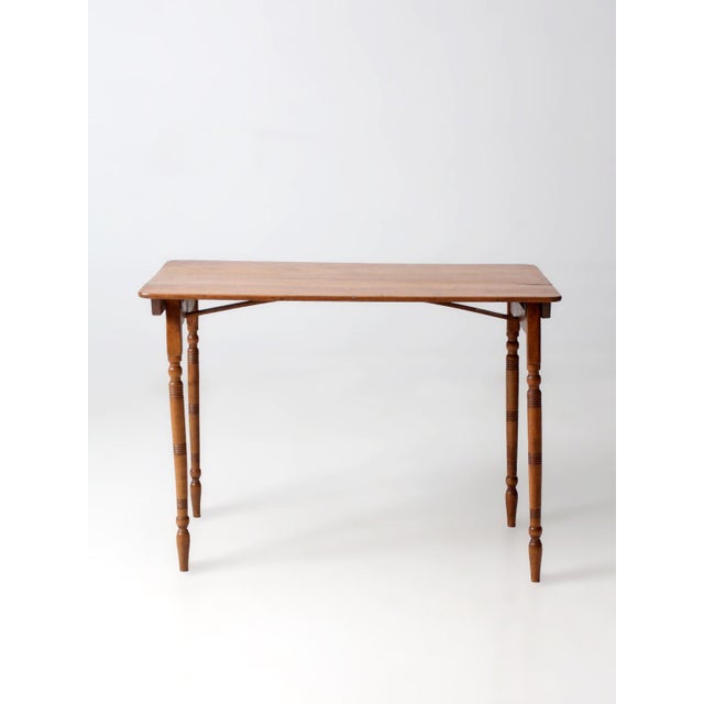 This late 19th century folding sewing table features a carved measuring rule and turned tapering legs. The rectangular top...