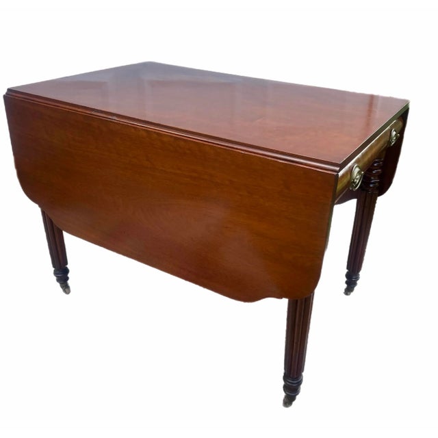 Classic Sheraton New England drop leaf table: Thick reeded legs with turned detail, terminating in brass casters. Single...