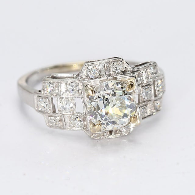 This is a vintage platinum art deco style ring with sixteen accent diamonds surrounding the ~0.8ct Old European Cut...
