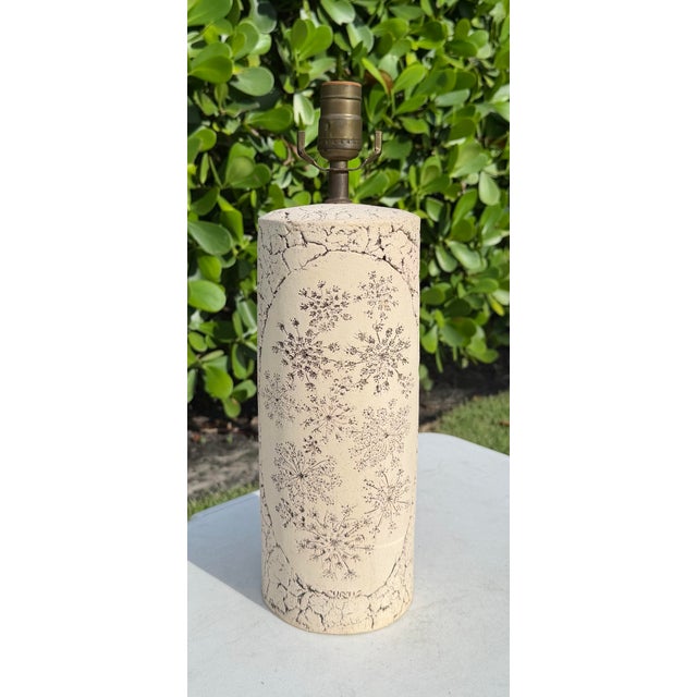 Vintage Curtis table lamp with a heavily textured, aged finish in warm ivory and cream. The body features a plaster-like...
