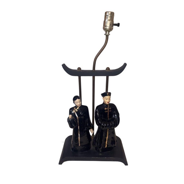 Gorgeous and unique black ceramic lamp featuring figurines of an Oriental couple, circa 1950. Small areas of chipping on...