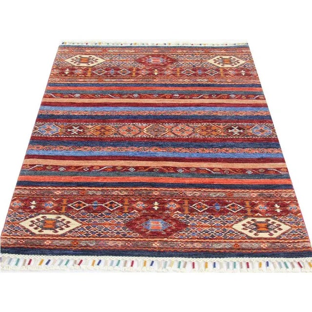 Handwoven Turkmenistan rug featuring geometric motifs in royal blue, peach, and red that are contained within horizontal...