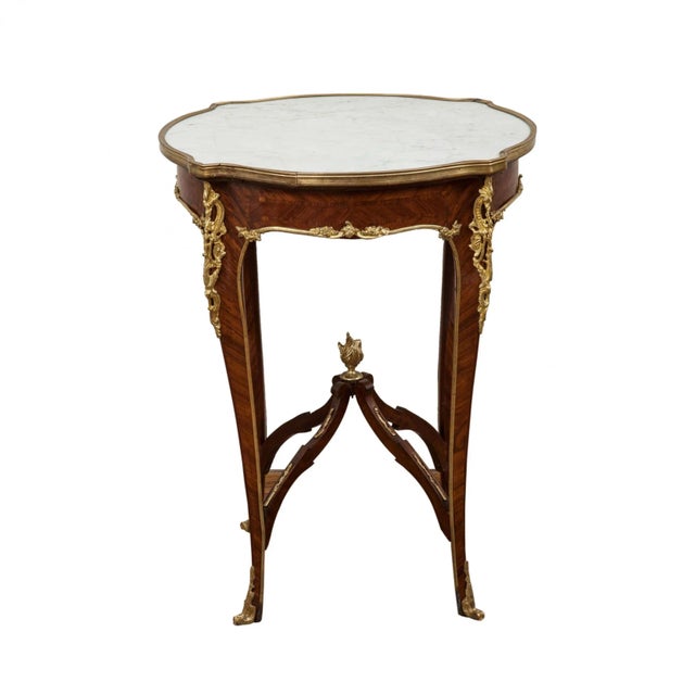 An elegant salon table with a marble top, marquetry texture, and gilded bronze cords. A simple shape, made in the Rococo...