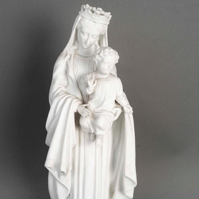 Early 20th-century sculpture depicting the Virgin Mary with the infant Jesus, made of biscuit porcelain. H: 53.5 cm, D: 20 cm