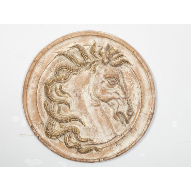 An Italian painted and gilt terracotta medallion from the early 20th century depicting a horse's head seen in profile....