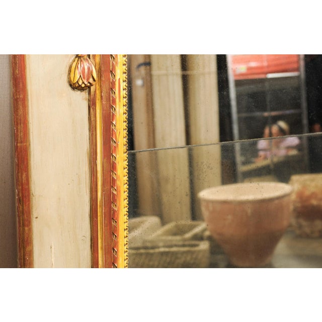 A French Neoclassical carved and painted wood mirror, with its original glass, from the 19th century. This antique mirror...