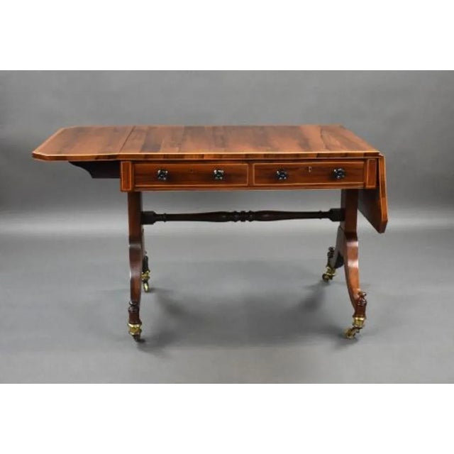 For sale is a good quality Regency rosewood sofa table, the rosewood top with banded edge and two drop leaves, with a...