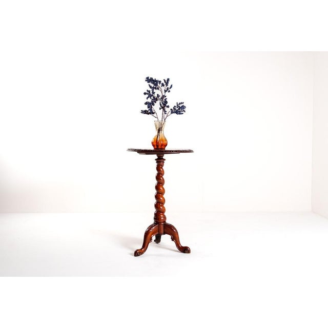 This vintage mahogany tripod table features a charming circular top resting upon an intricately designed barley twist...