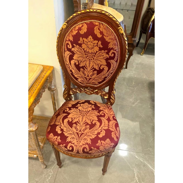 Elegant and richly detailed, this French Louis XVI style chair features a refined burgundy damask upholstery adorned with...