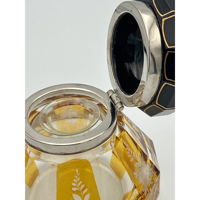 A striking vintage glass inkwell featuring an octagonal cut glass body with warm yellow amber panels and delicate etched...