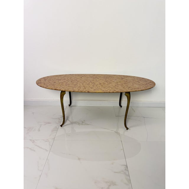 Oval brass coffee table with a marble top, 1950s. Intact and in good condition. Width 116 cm, depth 48 cm, height 42 cm.