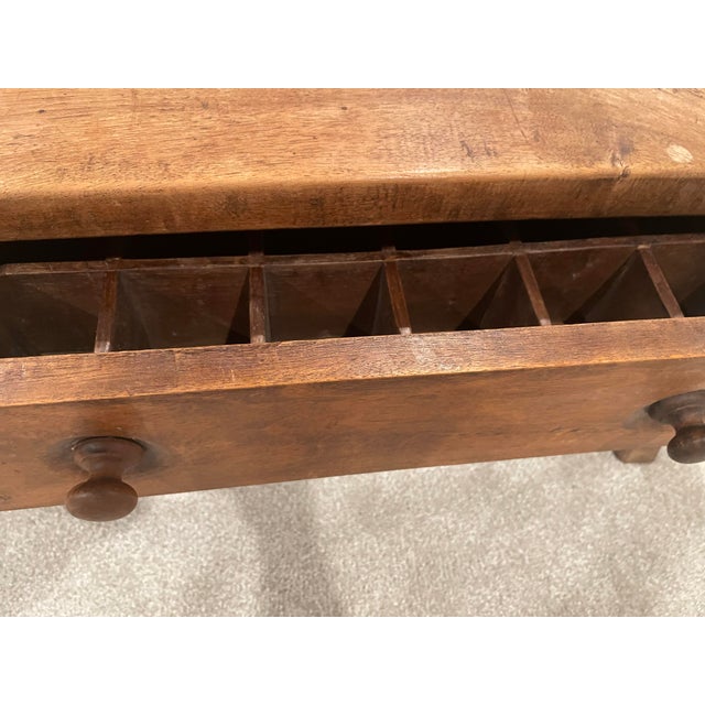This charming antique yew wood cobbler’s bench has been thoughtfully repurposed as a table in front of a small sofa bed in...