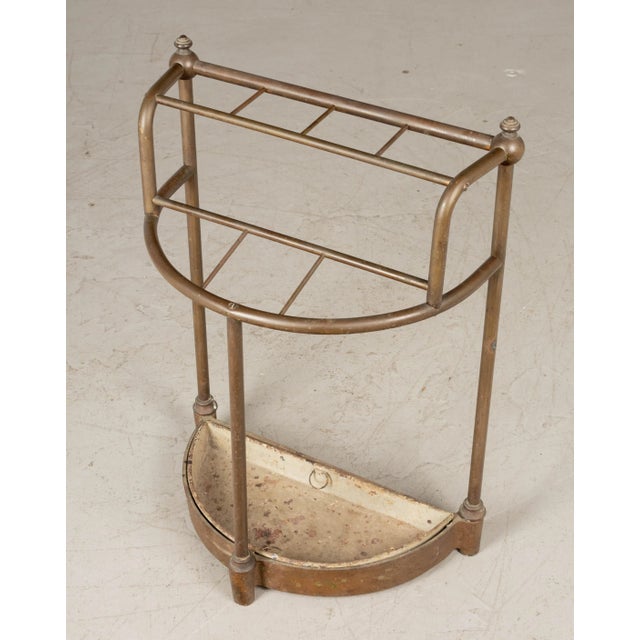 A 19th Century French brass and cast iron umbrella stand. Demilune form with brass tubing and decorative finials. Cast...