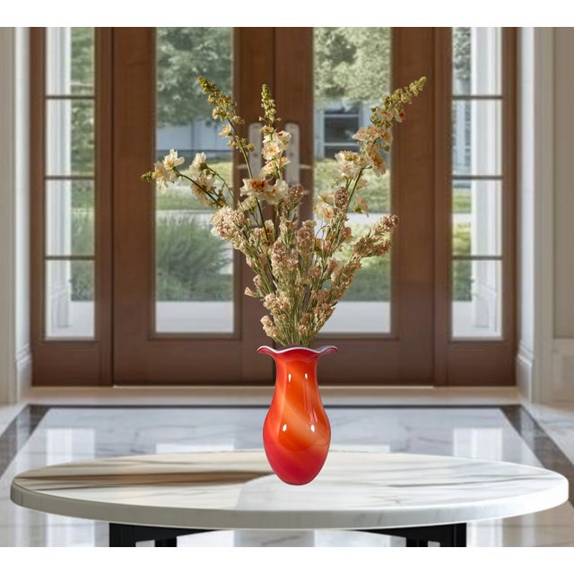 A striking hand-blown art glass vase executed in a classic Murano-style form, showcasing a vibrant blend of fiery red,...