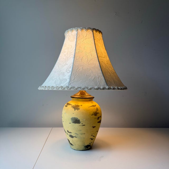 Vintage, custom, and refurbished yellow terracotta table lamp with patina'd brass accents. The lamp is paired with a...