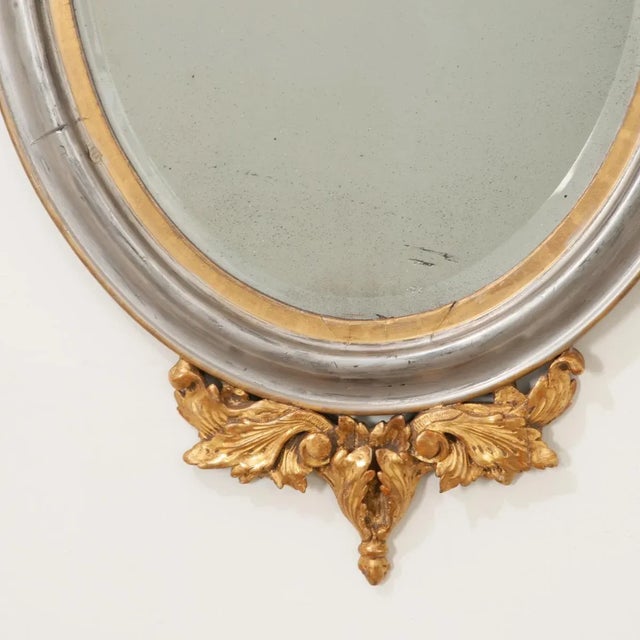 A regal gold and silver gilt mirror with intricate, carved details at the top and bottom. A splendid Ho-oh bird (or...