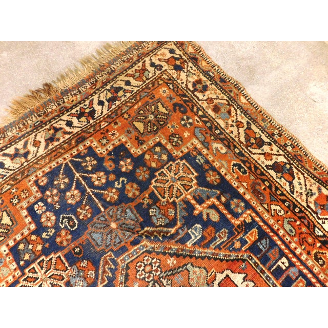 Antique hand-knotted Persian tribal Qashqai rug featuring prominent central geometric diamond medallion, deep navy and...