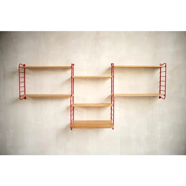 Robert Charroy, rare wall bookcase in red lacquered metal and oak edited by Mobilor, France 1950. The solid metal ladders...