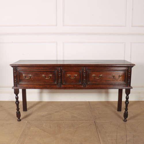 Early 19th century English three draw oak dresser base with turned legs. Nice colour and a great size. 1820. This piece is...