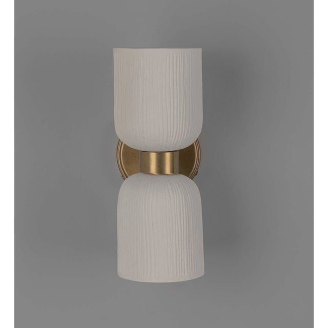 Handmade by Mullan Lighting, this wall sconce features matte, textured ceramic shades that are mounted on an antique brass...