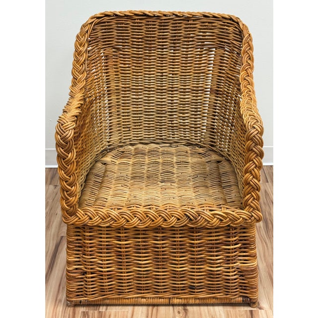 Classic vintage woven wicker lounge chair featuring braiding detail around the arms, back, and apron of the seat for a...