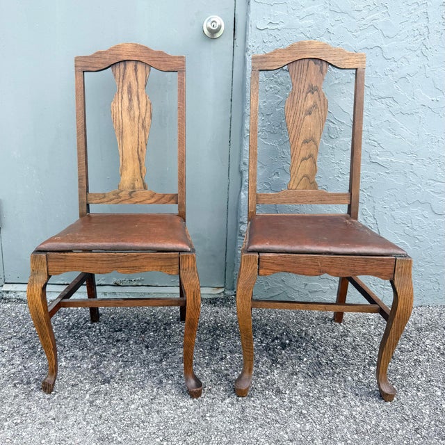 Charming pair of antique oak dining chairs featuring tall open backs, shaped center splats, and gently scalloped crest...