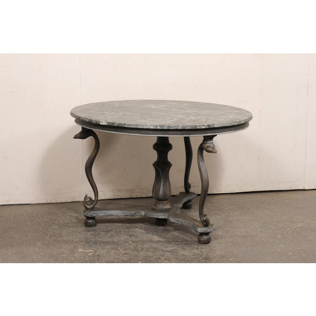 A French center table with serpent motif and green marble top. This vintage table from France features a round-shaped...