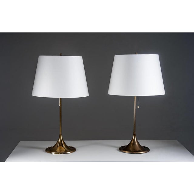 A refined pair of swedish brass table lamps with elegant, trumpet-shaped bases and slender stems. The design is balanced...