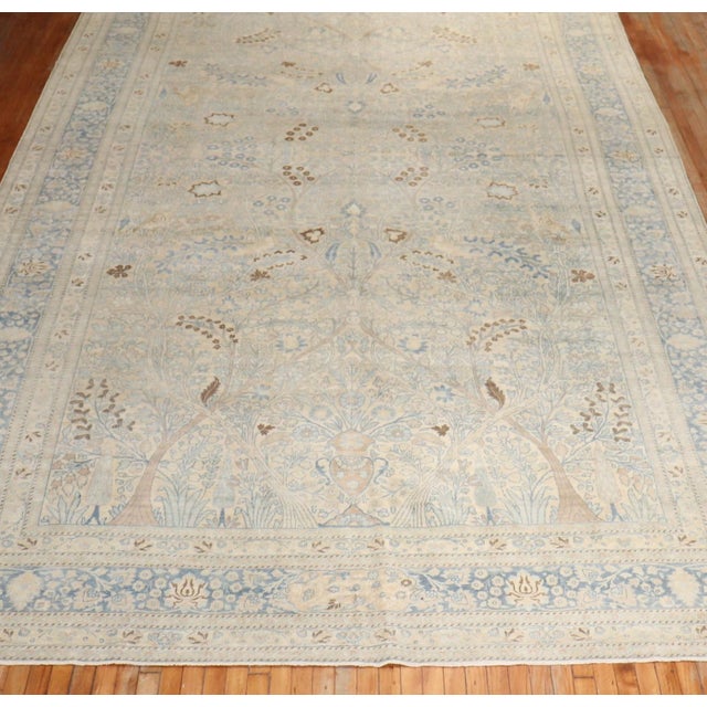 An early 20th Century Persian Meshed Oversize Rug. A paradise directional pattern in brown blue and ivory on a khaki field