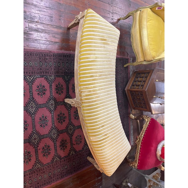 This graceful bench features a carved wood frame with fluted legs and rosettes, finished in a lightly distressed gilt...